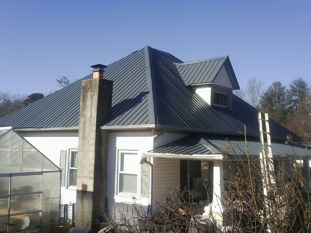 Dark blue standing seam metal roof on a white farmhouse with dormer — Slate & Tile Roof Repair by Roofing Brothers in Blackfoot