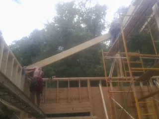 Carpenter raising a rafter beam on a new second story frame in Blackfoot