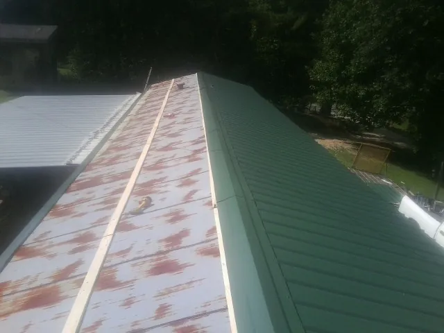 Old rusted panels beside newly installed green metal roofing — Wind Damage Roof Repair by Roofing Brothers in Blackfoot