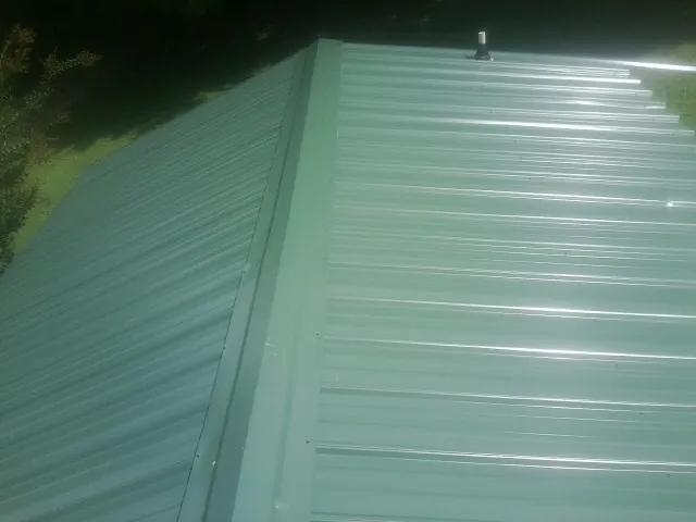 New green metal panels meeting at the ridge of a roof — Flat Roof Repair work by our crew in Blackfoot