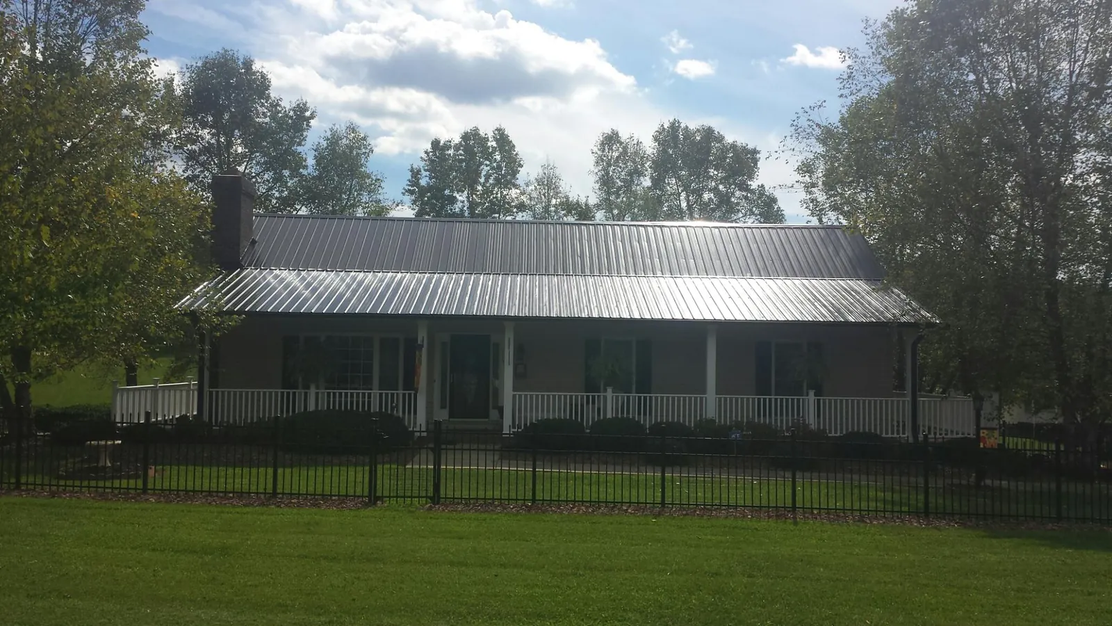 Gray metal roof on a brick ranch with a full width front porch — Gutter Guard Installation work by our crew in Blackfoot