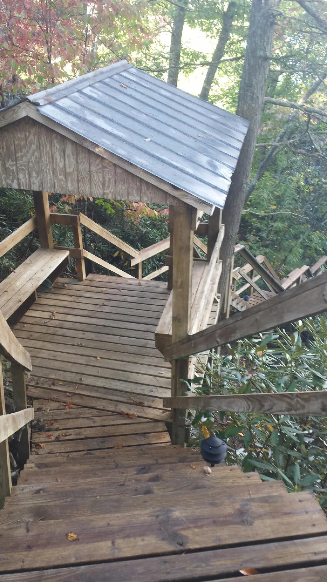 Metal roofed shelter over wooden steps on a wooded walkway — Skylight Repair & Installation work by our crew in Blackfoot