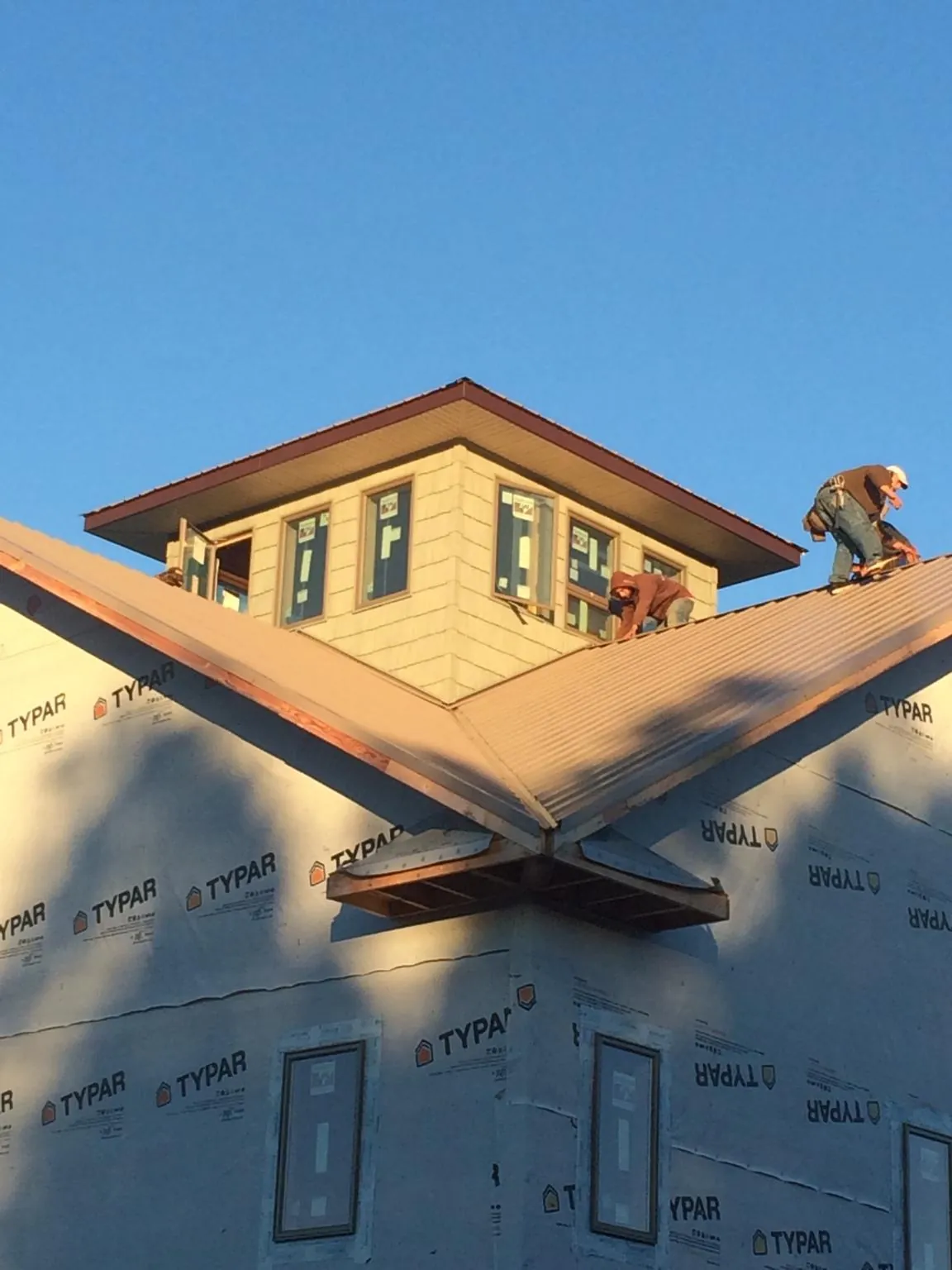 Roofers working around a rooftop cupola on a new metal roof at sunset — Roof Waterproofing in Blackfoot by Roofing Brothers